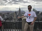Steven, Mitglied des Showensembles des Kreuzfahrtschiffs Grand Lady, posiert mit New York-T-Shirt auf der Aussichtsplattform des Rockefeller Centers, Top of the Rocks, vor der weltberühmten Skyline von New York City