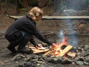 Bear Brown tending to a campfire.