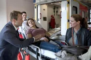 Yasmin (Sophie Dal, M.) hat einen Zusammenbruch. Besorgt beobachten ihr Mann Lars Meckel (Matthias Ziesing, l.) und Gudrun (Katrin Pollitt, r.) ihren Abtransport mit dem Krankenwagen.