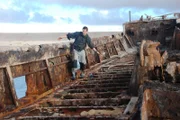 Bear Grylls running over the deck of the rusty shipwreck.