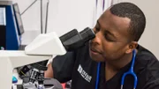 Dr. Blue looks in a microscope.