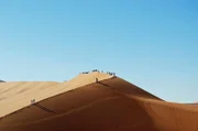 Die Reisenden erkunden die scheinbar endlose Wüste mit ihrer herrlichen Dünenlandschaft.