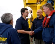 Principal Marine Archeologist Neil Cunningham Dobson greets U-boat expert Axel Niestle, along with Senior Project Manager Tom Dettweiler and Project Manager Mark Martin, and  aboard the Odyssey Explorer.