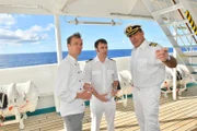 Die Freunde Chief Purser Holger (Daniel Wiemer, M.) und Sous-Chef Thomas (Max Woelky, l.) werden von Kapitän Burger (Sascha Hehn, r.) von der Erpressung unterrichtet.