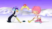 Zoé spielt mit einem Pinguin Eishockey. Der Puck liegt bereit.