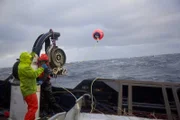 The crew for the Saga drops a pot and one deckhand throws the buoy.