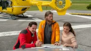 Tobias (Markus Brandl, l.), Markus (Sebastian Ströbel, M.) und Lara Fellner (Leonie Rainer, r.) besprechen am Heliport die weitere Vorgehensweise.