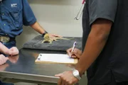 Coconut the Bearded Dragon placed between Dr. Ross and his parents on the evaluation table
