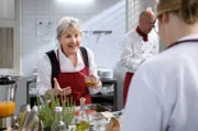 Hildegard (Antje Hagen, l.) unterhält sich beim Kochen mit Josie (Lena Conzendorf, r. mit Komparse) auch über private Dinge.