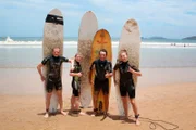 Zweiter Offizier Christian Baumann, Entertainment-Managerin Cori und Mitglied des Showensembles Esther üben sich als Surfer in Buzios, Brasilien.