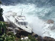 Die Wellen drücken das Boot der Küstenwache gegen die Felsen