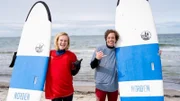 Wie der Checker eine perfekte Welle reitet, das zeigt ihm Surflehrerin Fiona am Meer.