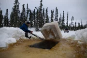 Jessi Morse hilft, den Eisblock mit einem Ast freizulegen, während Chris Morse ihn mit seinem Schneemobil herauszieht. (National Geographic/Patrick Henderson)