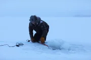 Johnny Rolfe setzt sein Fischernetz unter das Eis des Ackerman Lake. (National Geographic/Mike Fennell)