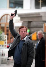Kommissar Wallander (Krister Henriksson, links) legt seine Waffe nieder, um sich gegen eine Geisel auszutauschen.