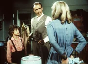 Nellie Oleson (Alison Arngrim, r.) verbirgt eine Schürze mit roten Flecken, die sie und ihr Bruder Willie (Jonathan Gilbert, l.) in ihrer Küche gefunden haben, vor ihrem Vater (Richard Bull, M.).