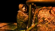 Deckhand Nick Mavar, secures pots on the stack with ties at night.