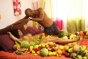 Jamar and Vanessa in bed with fruit.