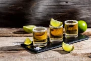 Mexican Gold Tequila with lime and salt on rustic wooden background.