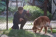 Nico (Samuel Schneider) lockt einen Hund mit einem Würstchen zu sich.