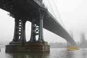 A New York Water Taxi passes under Manhattan Bridge as fog encloses the city. (National Geographic/Adam Simon)