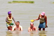 Bordarzt Dr. Winfried "Winnie" Koller und Stellvertetender Kreuzfahrtdirektor Jörn Hofer werden nach dem Bad im Schlammvulkan von Totumo in Kolumbien von zwei einheimischen Frauen im Fluss gewaschen