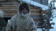 Heimo Korth outside cabin preparing to hunt for moose on snow mobile.