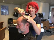 Friseurin Chiara schneidet Bordarzt Winfried "Winni" Koller im bordeigenen Friseursalon die Haare.