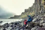 L-R: Benedict Cumberbatch und Bear Grylls unterhalten sich auf den Felsen der Isle of Skye in Schottland. Bear Grylls nimmt Benedict Cumberbatch mit auf die zerklüftete Isle of Skye, wo Benedict seine Widerstandsfähigkeit auf die Probe stellen wird, während sie nach einer Reihe von versteckten Verstecken suchen, die wichtige Vorräte enthalten, die sie zum Überleben an den eisigen Küsten des Nordatlantiks benötigen. (National Geographic für Disney/Ben Simms)