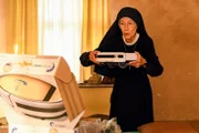 Schwester Felicitas (Karin Gregorek) packt einen Saugroboter aus.