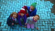Kinder malen mit blauer Straßenkreide den Bürgersteig an.