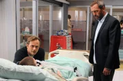 Als House (Hugh Laurie, r.) Roy Randall (Lee Tergesen, l.) das baldige Sterben seines Sohnes Jack (Tanner Maguire, lieg.) ankündigt, will dieser das nicht wahrhaben und glaubt, mit Hilfe des Karmas seinen Sohn retten zu können.