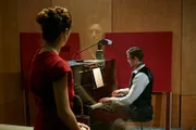 Eine Frau schaut einem Mann beim Klavierspielen zu