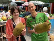 Auf dem Markt von Mahé erfahren Küchenchef Patrick Müller und Praktikantin Theresa mehr über lokale Spezialitäten und probieren eine Jackfruit.