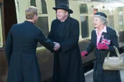 Father Brown (Mark Williams, M.) und Mrs. McCarthy (Sorcha Cusack, r.) begrüßen Pater Franc (Rod Hallett, l.) bei seiner Ankunft am Bahnhof.