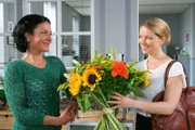 Noch glaubt Controllerin Ortmann (Diana Staehly, r.), dass der Blumenstrauß für sie bestimmt ist. Sekretärin Stockl (Marisa Burger, l.) freut sich mit ihr.