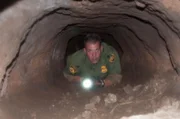Nogales, AZ: An agent looking through an underground tunnel. Claustrophobic tunnels like these could be infested with cockroaches and other parasites.