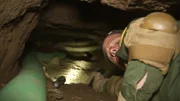 Nogales, AZ: An armed agent looking back while going through an underground tunnel. Armed with just a handgun, agents can barely squeeze through the claustrophobic passage.
