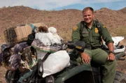 Nogales, AZ: An agent sitting on an ATV loaded with confiscated bundles of smuggled goods. Smugglers regularly attempt to carry marijuana into the USA, and carry drug payments and weapons into Mexico.