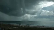 A waterspout seen from the beach over the ocean.