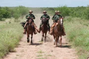 Laredo, TX: Customs and Border Protection agents riding horses along the border. Agents use different means of transportation to get through the terrain.