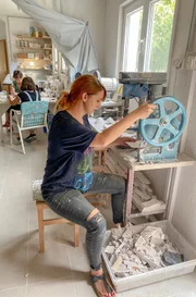 In der Werkstatt der Familie Jaksic bereitet Dina kleine Plättchen für das berühmte Kalksteinkleid vor.