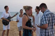 Passagier Lukas macht seiner Freundin Daniela am Strand von Colombo, Sri Lanka, einen Heiratsantrag. Im Hintergrund sorgen Steven Timmermann, künstlerischer Leiter an Bord, und seine Gruppe für musikalische Begleitung.