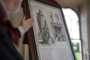 Ein Mann zeigt auf eine Tafel mit Informationen über St. Nicholas