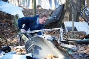 Investigator Bob Benzon (played by Kevin Carter) examines the debris at the Alitalia flight 404 crash site.