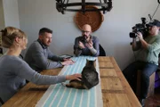 Jackson, Moran family, and crew member sitting at a table where Zachary is laying.