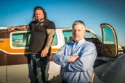 Ken Cage and Danny Thompson standing in front of a car outside.