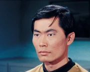 Lieutenant Hikaru Sulu (George Takei) sitzt am Navigationspult der Enterprise.