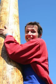 Willi beim Maibaumkraxeln im österreichischen Freinberg. Ohne Sicherung klettert er den Baum hinauf und nur das Baumharz, mit dem er die Hände und Füße eingerieben hat, gibt ihm Halt.