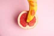 Flat lay composition with fresh banana and grapefruit on pink background. Sex concept